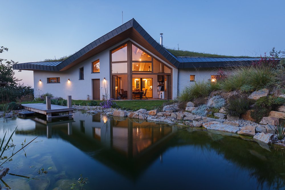 single story house with big windows overlooking a pond